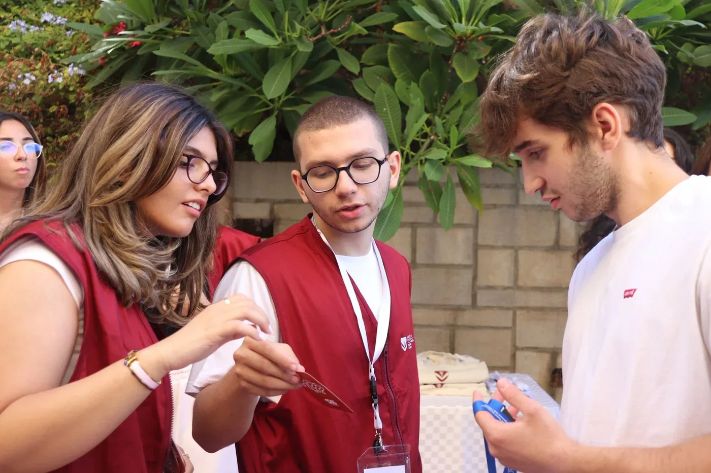 BSS members in maroon vests handing a membership card to a student on campus